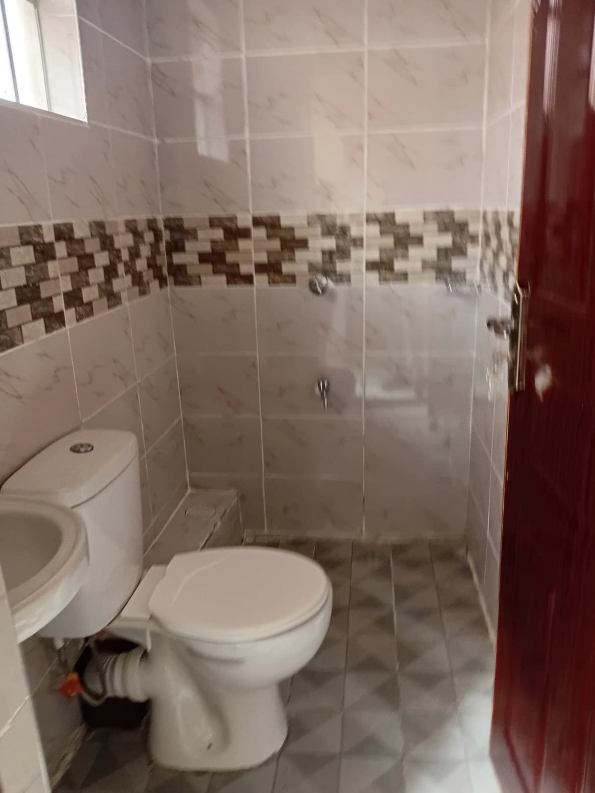 Compact bathroom with toilet and decorative tile border