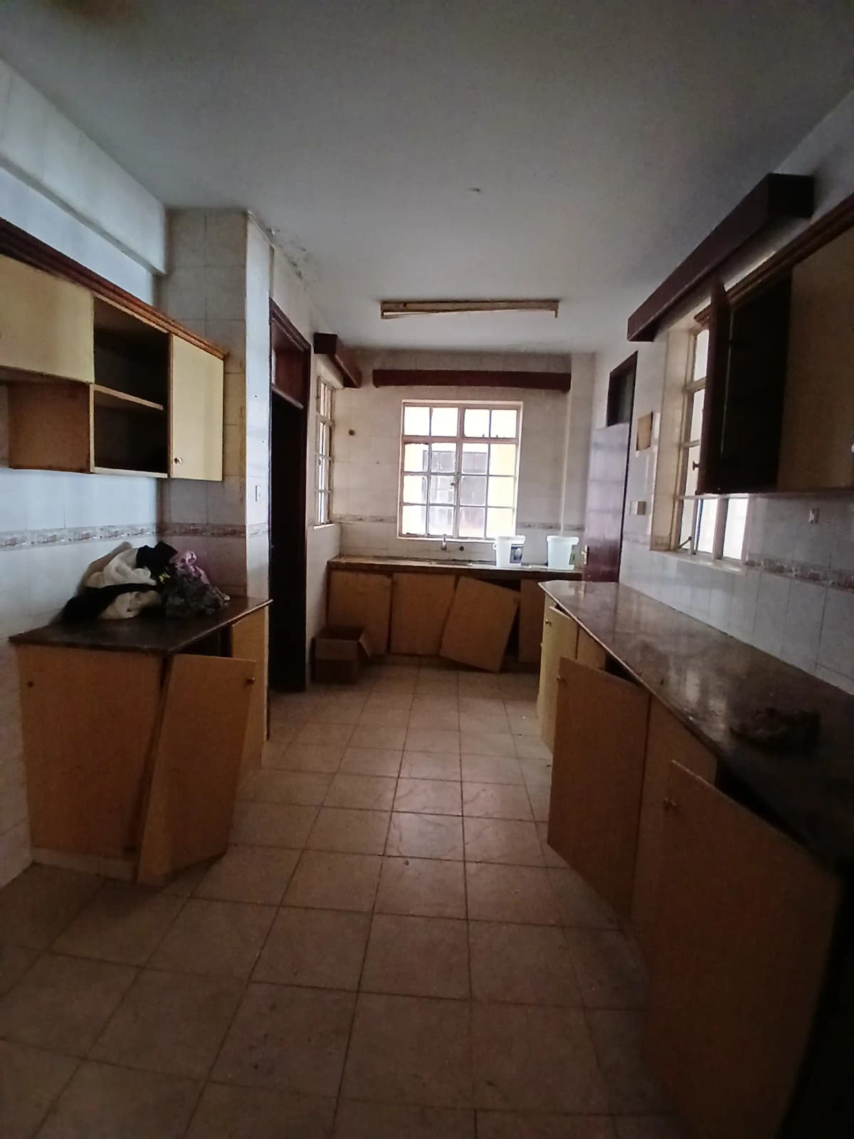 Galley kitchen with wooden cabinetry and tiled flooring