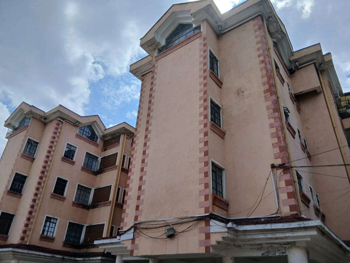 Multi-story residential building with pink facade and blue window frames