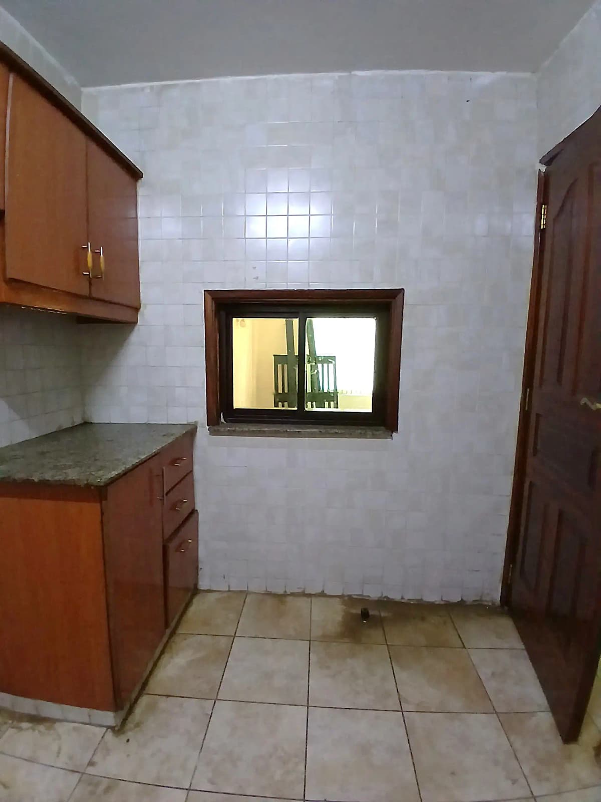 Compact kitchen with wooden cabinets and tiled floor