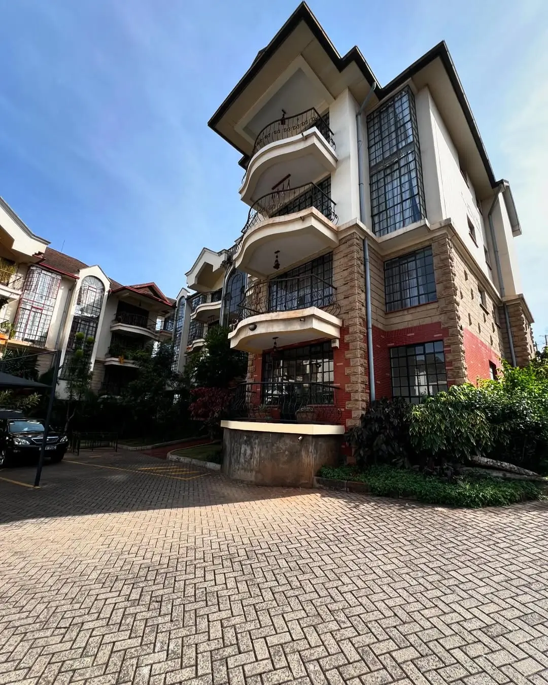 Modern multi-story residential building with curved balconies and brick facade