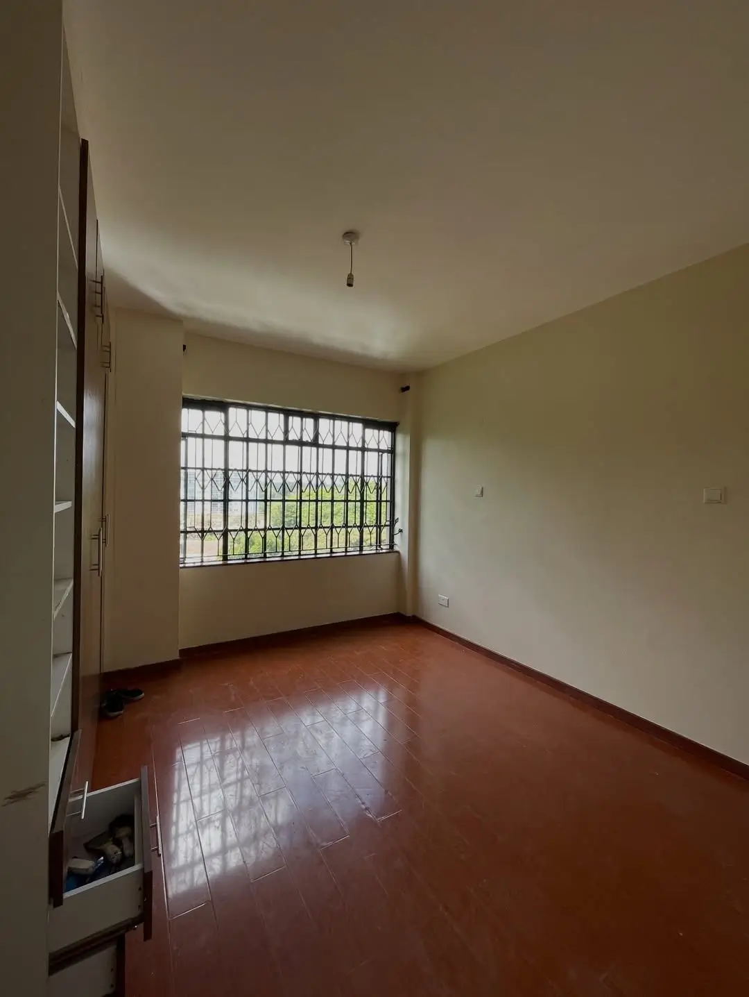 Spacious bedroom with terracotta floor and barred window