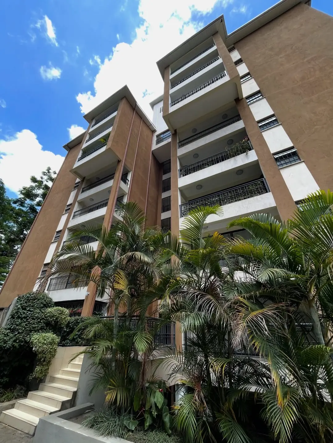 Modern mid-rise apartment building with tropical landscaping