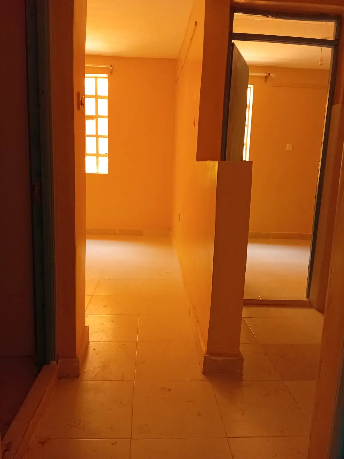 Empty corridor with orange tiled floor and brown wooden pillars