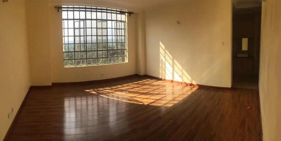 Spacious living room with wooden flooring and barred window