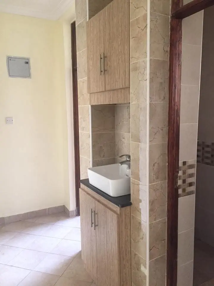 Bathroom with white basin, wooden cabinetry, tiled walls