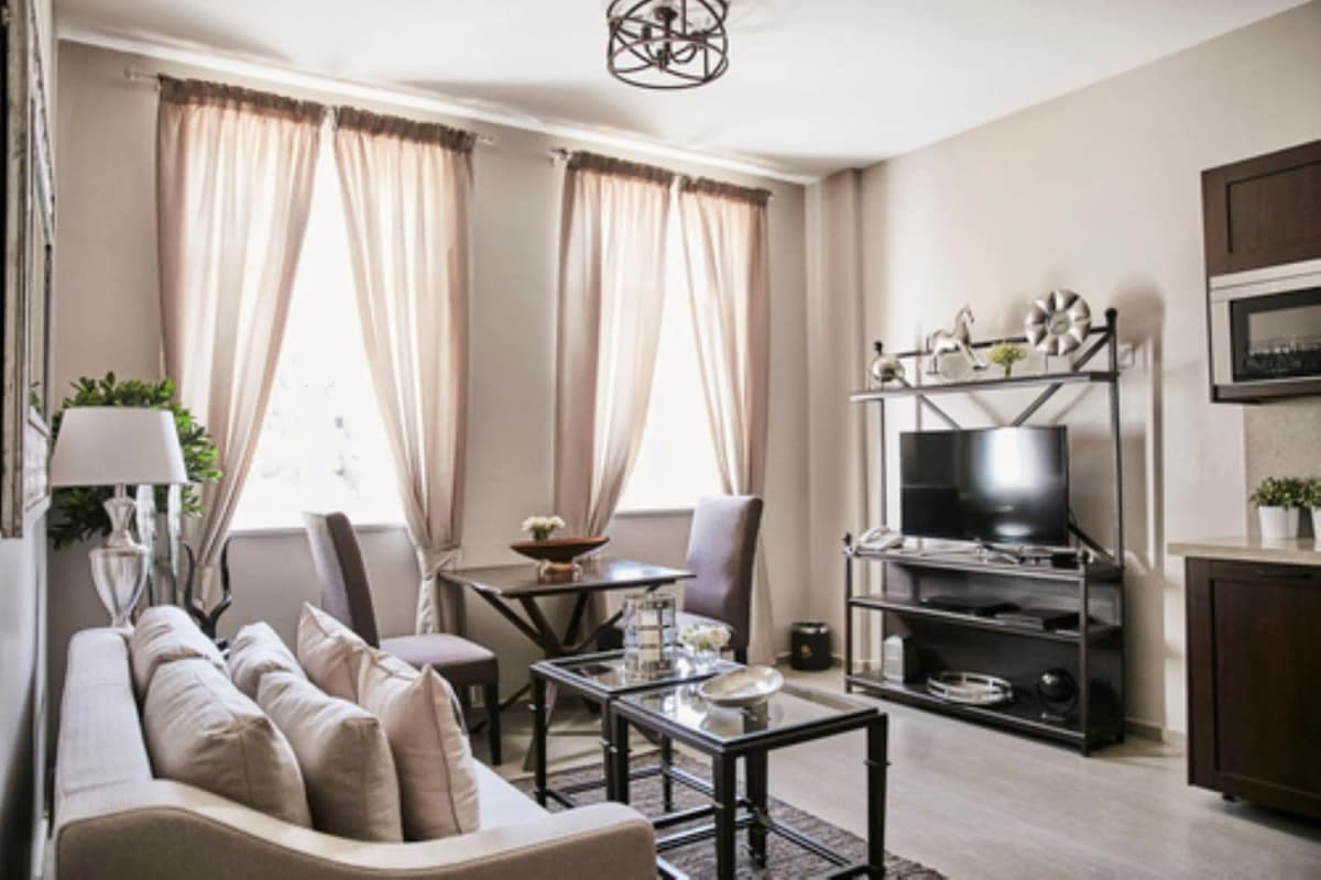 Bright living room with cream sofa, TV stand, large windows