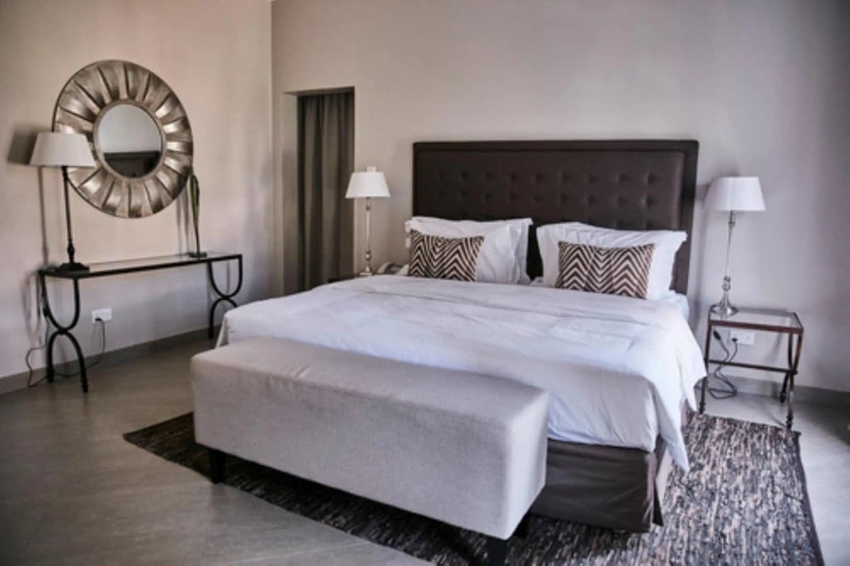 Master bedroom with dark upholstered headboard and white bedding