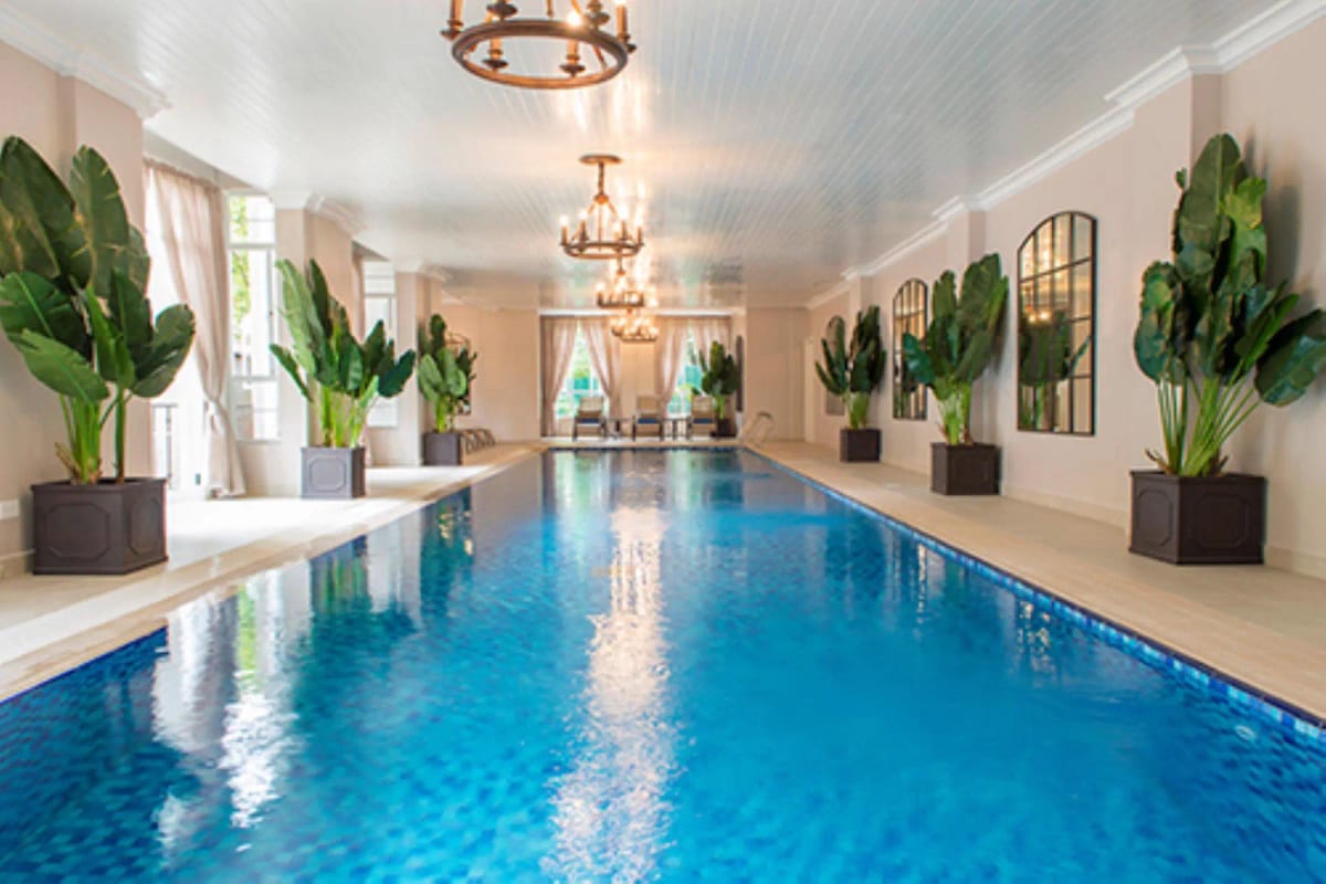 Luxurious indoor swimming pool with high ceilings and lush plants