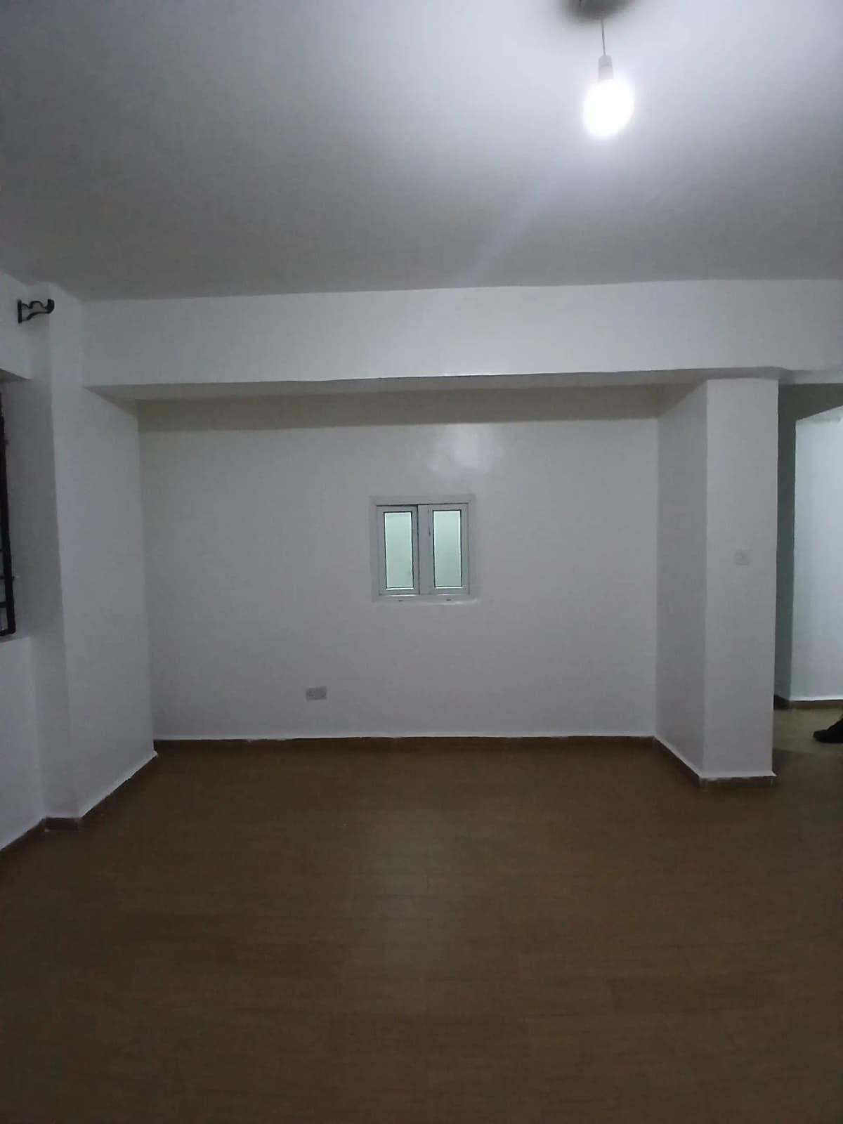 Empty living room with dark wood flooring and white walls