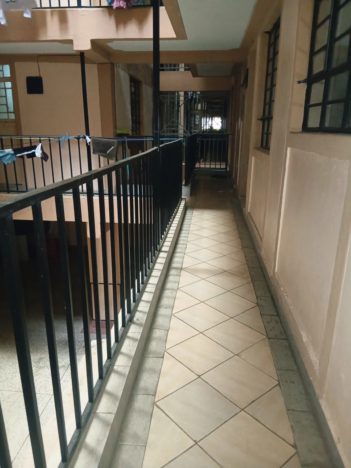 Multi-level corridor with black metal railings and tiled flooring