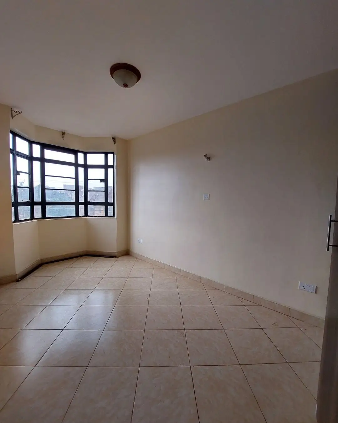 Spacious empty bedroom with bay window and tiled flooring