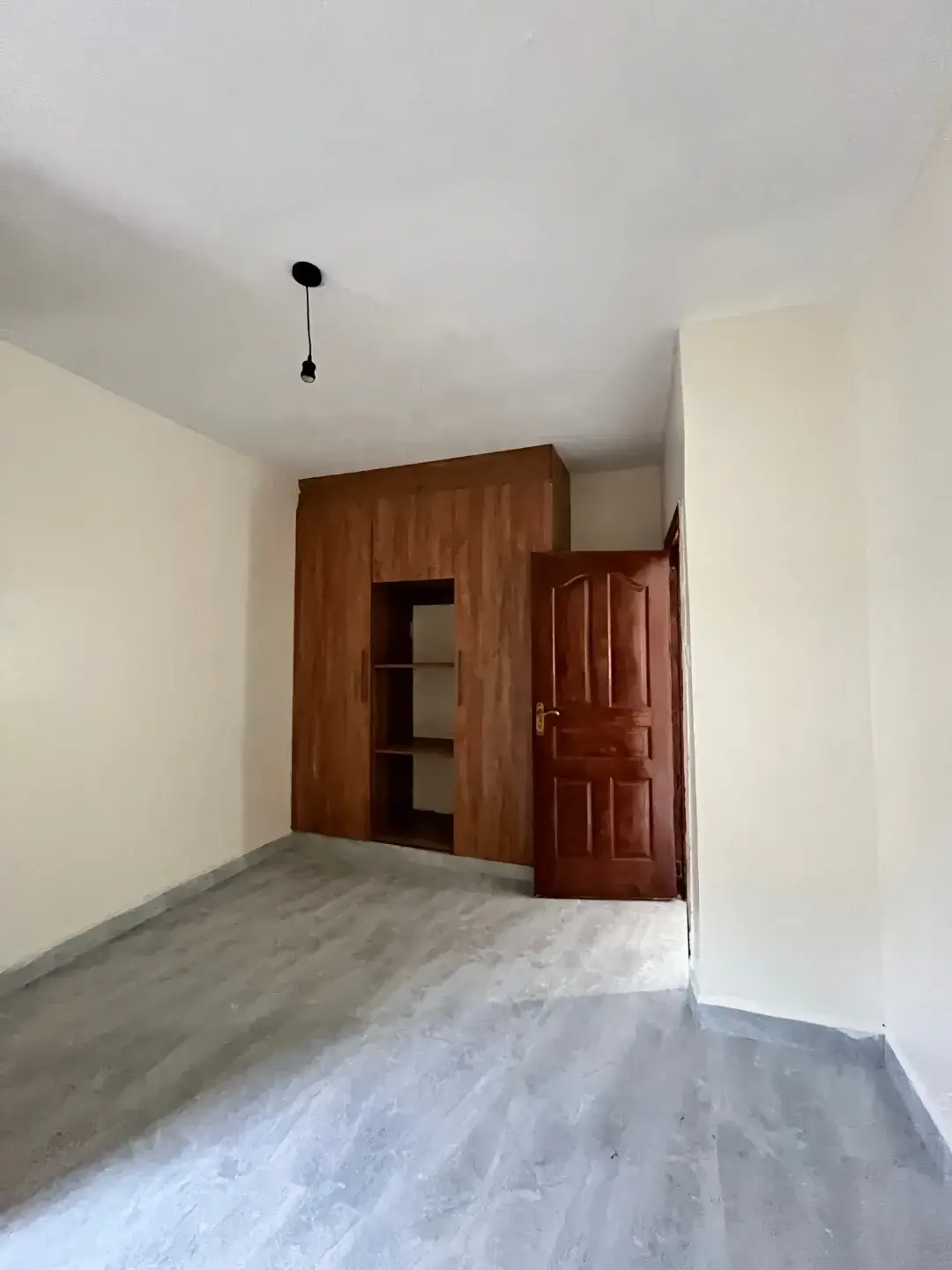 Spacious bedroom with wooden wardrobes and polished floor