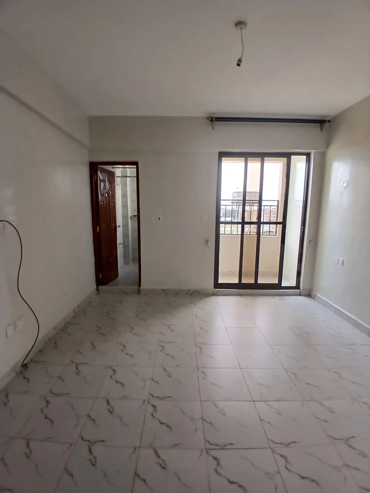 Bright empty living room with marble-effect flooring and balcony