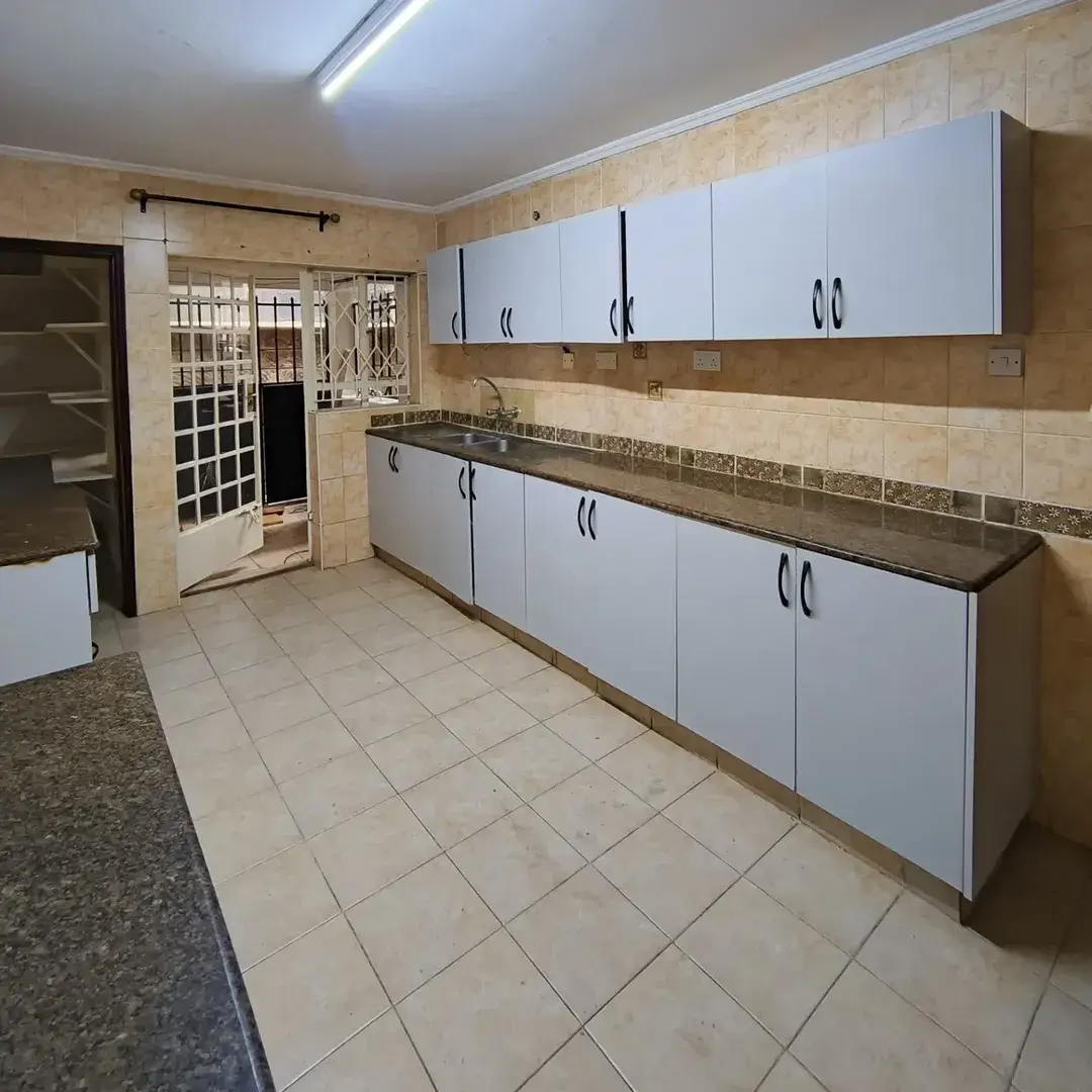 Spacious kitchen with white cabinets and dark granite countertops