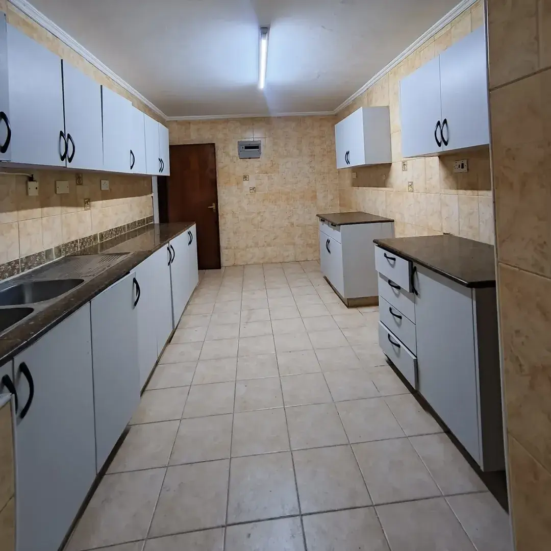 Galley kitchen with white cabinets, dark countertops, tiled floor