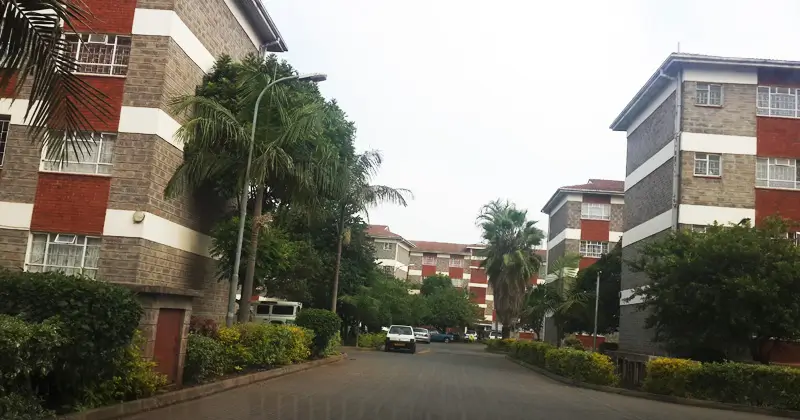 Multi-story residential compound with tree-lined driveway and landscaping
