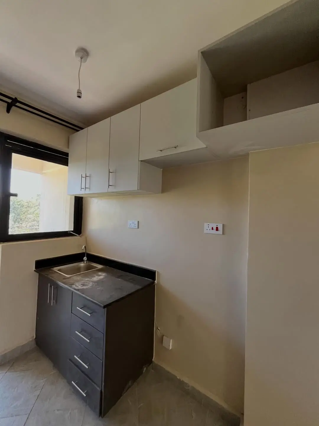 Compact kitchen with black base cabinets and white upper storage