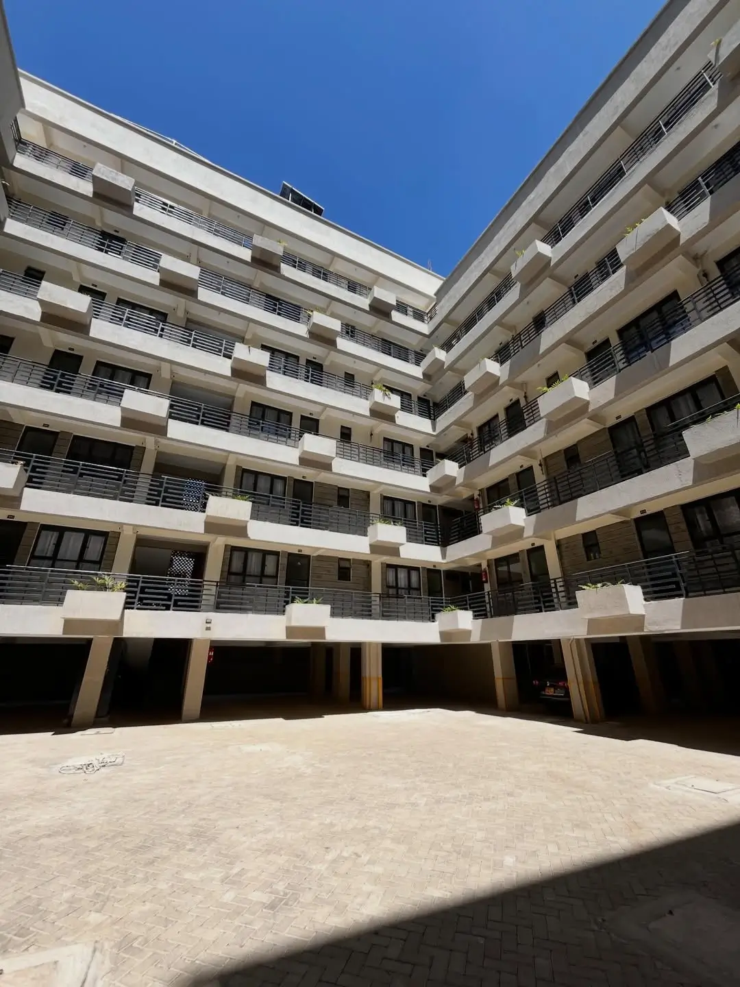 Modern multi-story residential building courtyard with parking below
