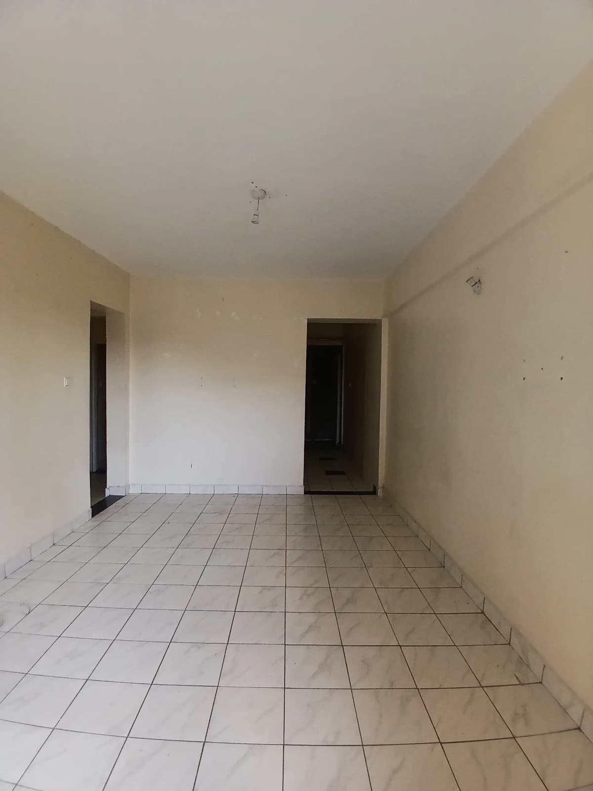 Empty living room with tiled flooring and neutral walls