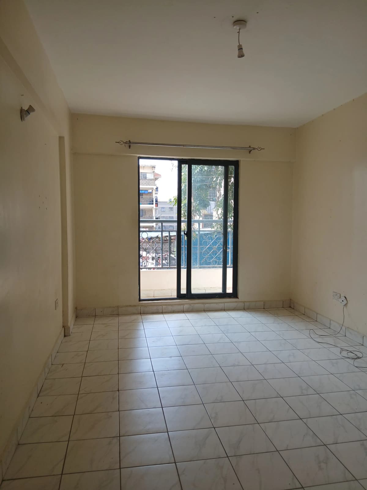 Bright living room with tiled flooring and glass balcony doors