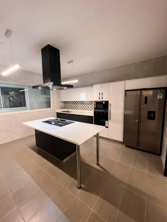 Modern open-plan kitchen with island, black hood, stainless appliances