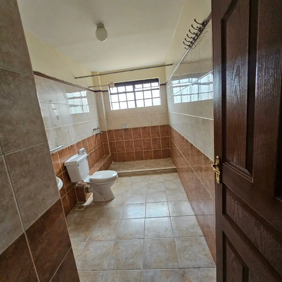 Spacious bathroom with toilet, shower enclosure, tiled walls