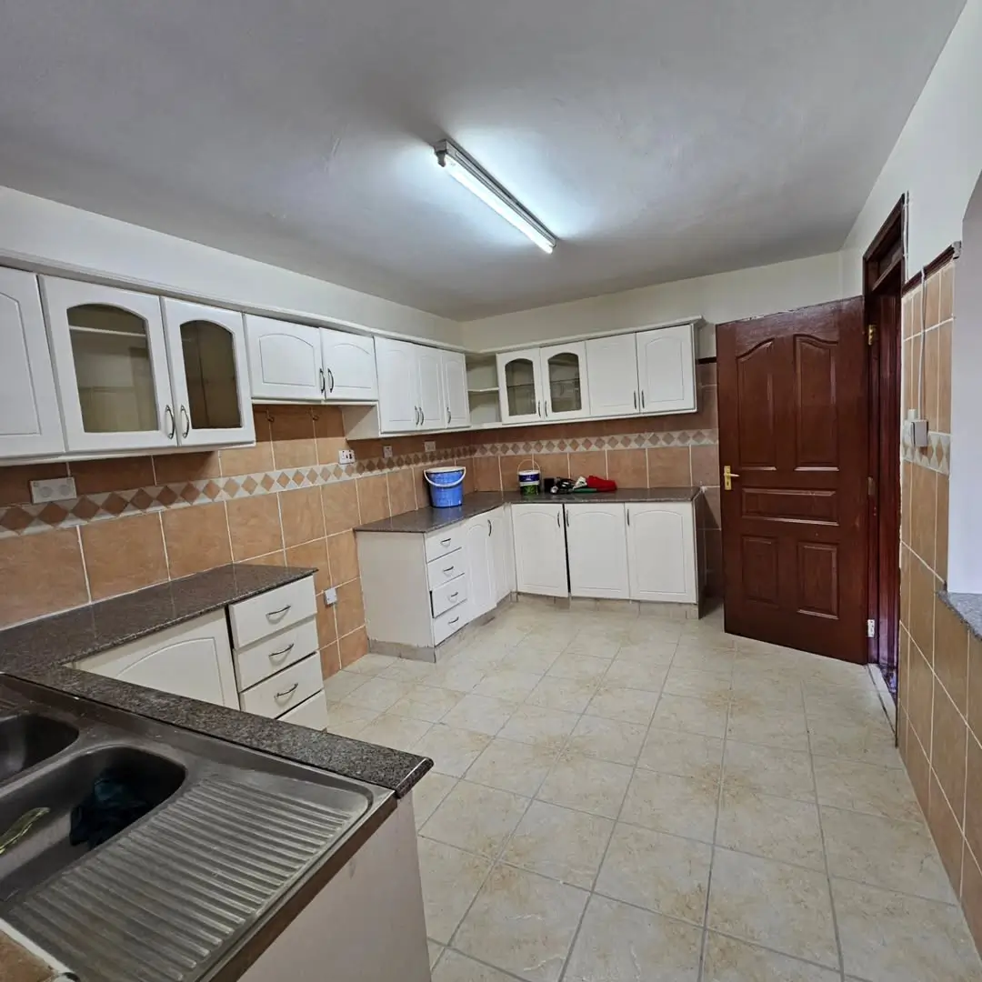 Spacious kitchen with white cabinets, brown tile backsplash, dark countertop