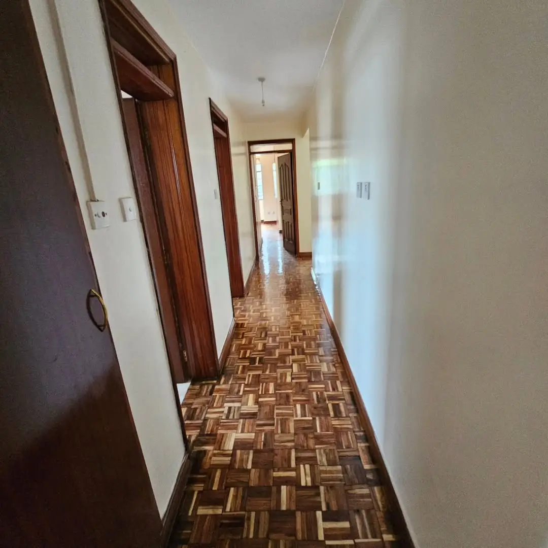 Long hallway with wooden doors and parquet flooring