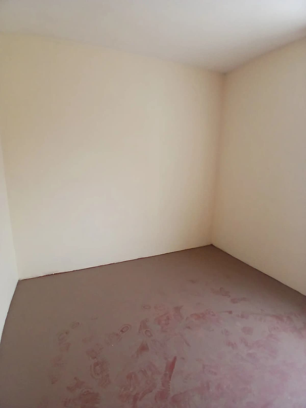 Empty bedroom with plain walls and concrete floor