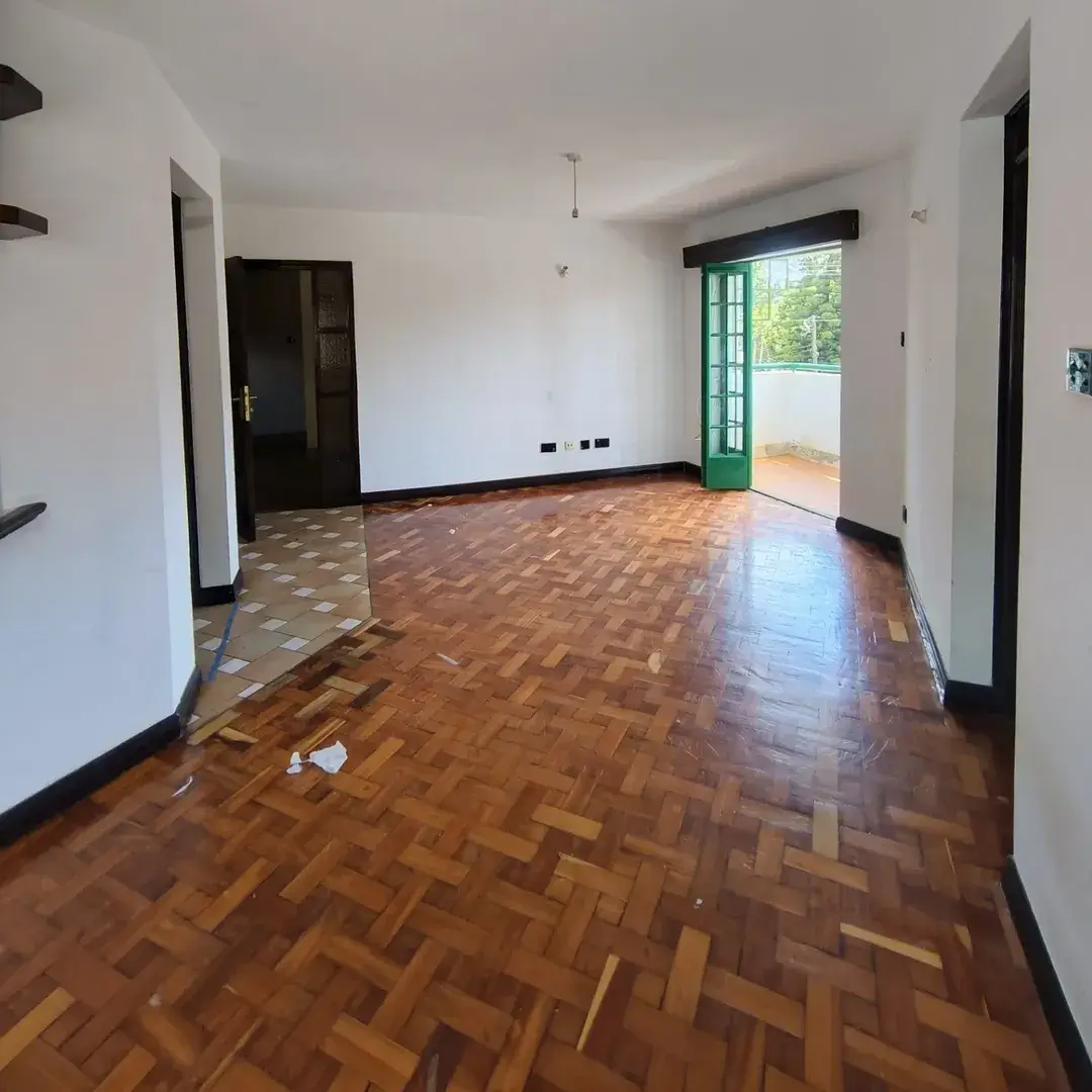 Spacious empty living room with parquet flooring and green balcony door