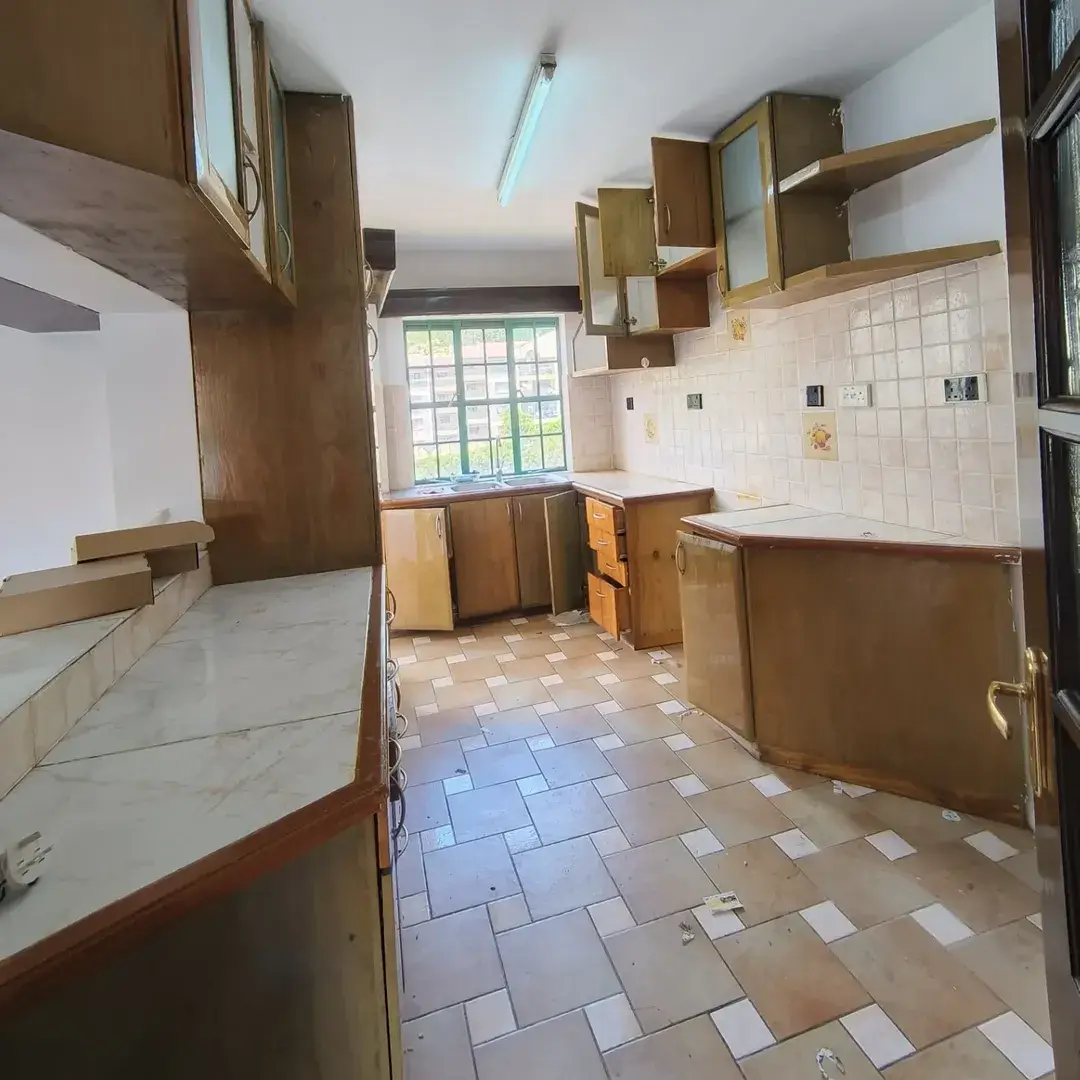 Spacious kitchen with wooden cabinets and tiled flooring.