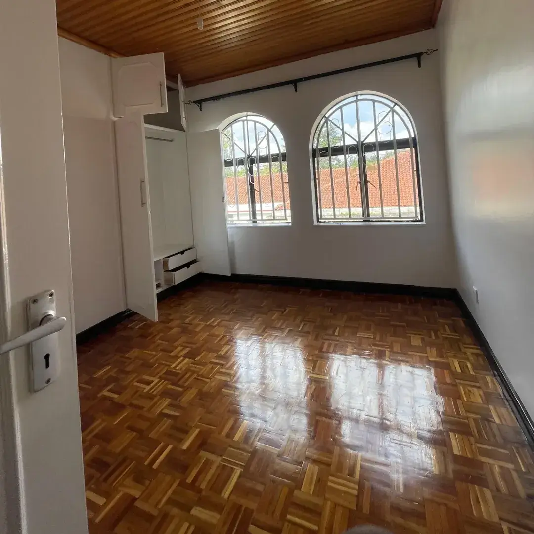 Spacious bedroom with wooden parquet flooring and arched windows