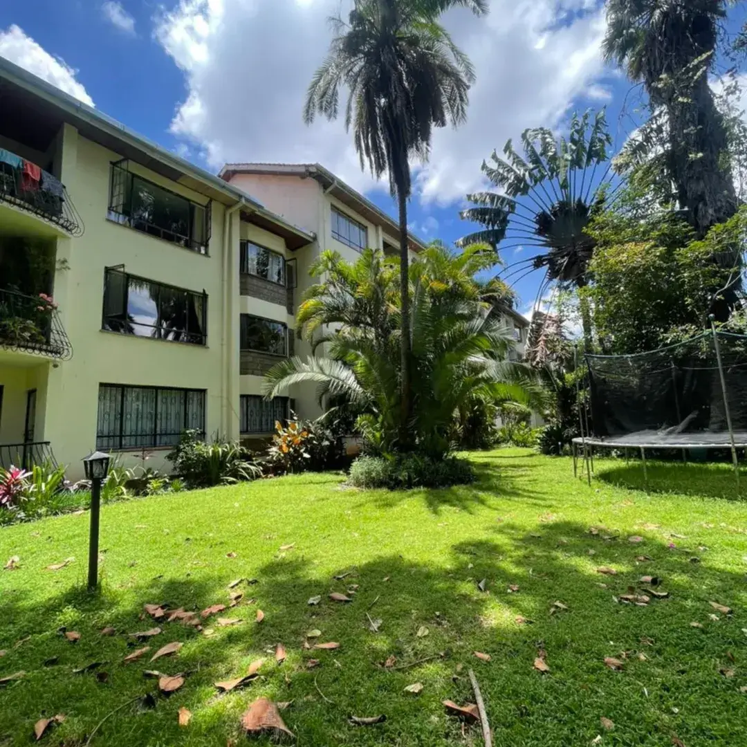Lush manicured lawn with palm trees and building backdrop