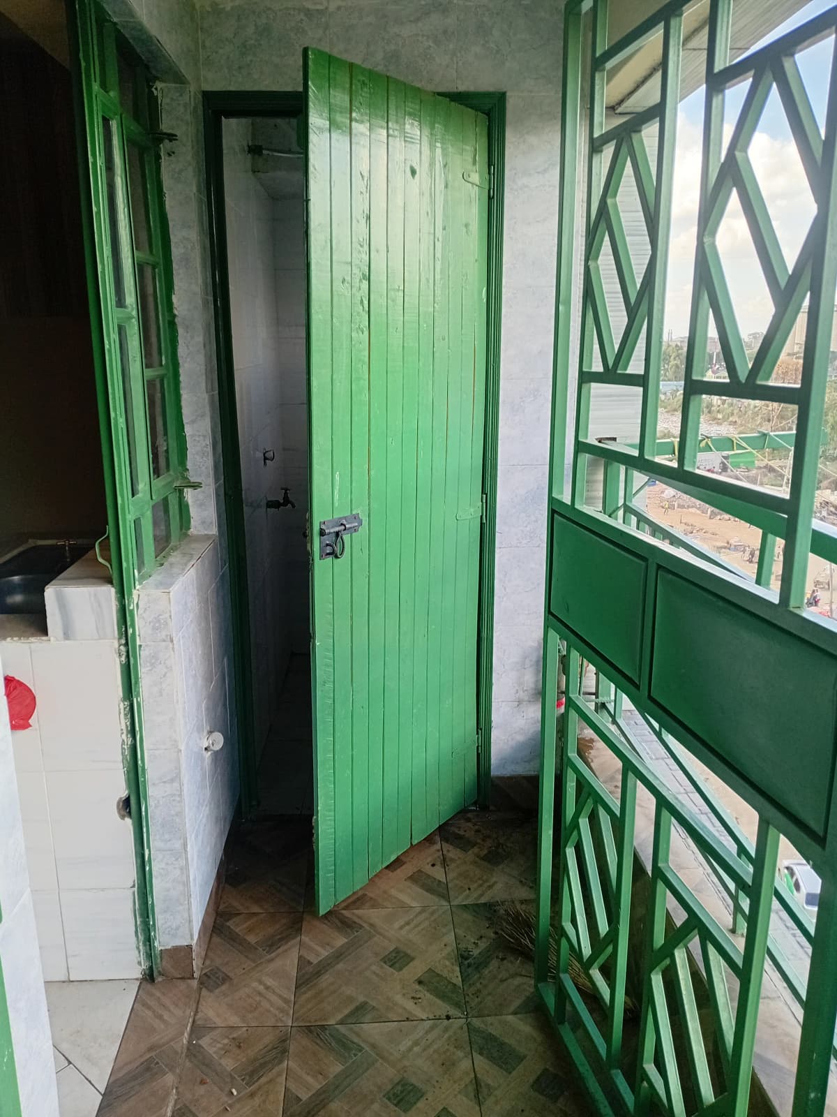 Compact bathroom with green door and tiled flooring
