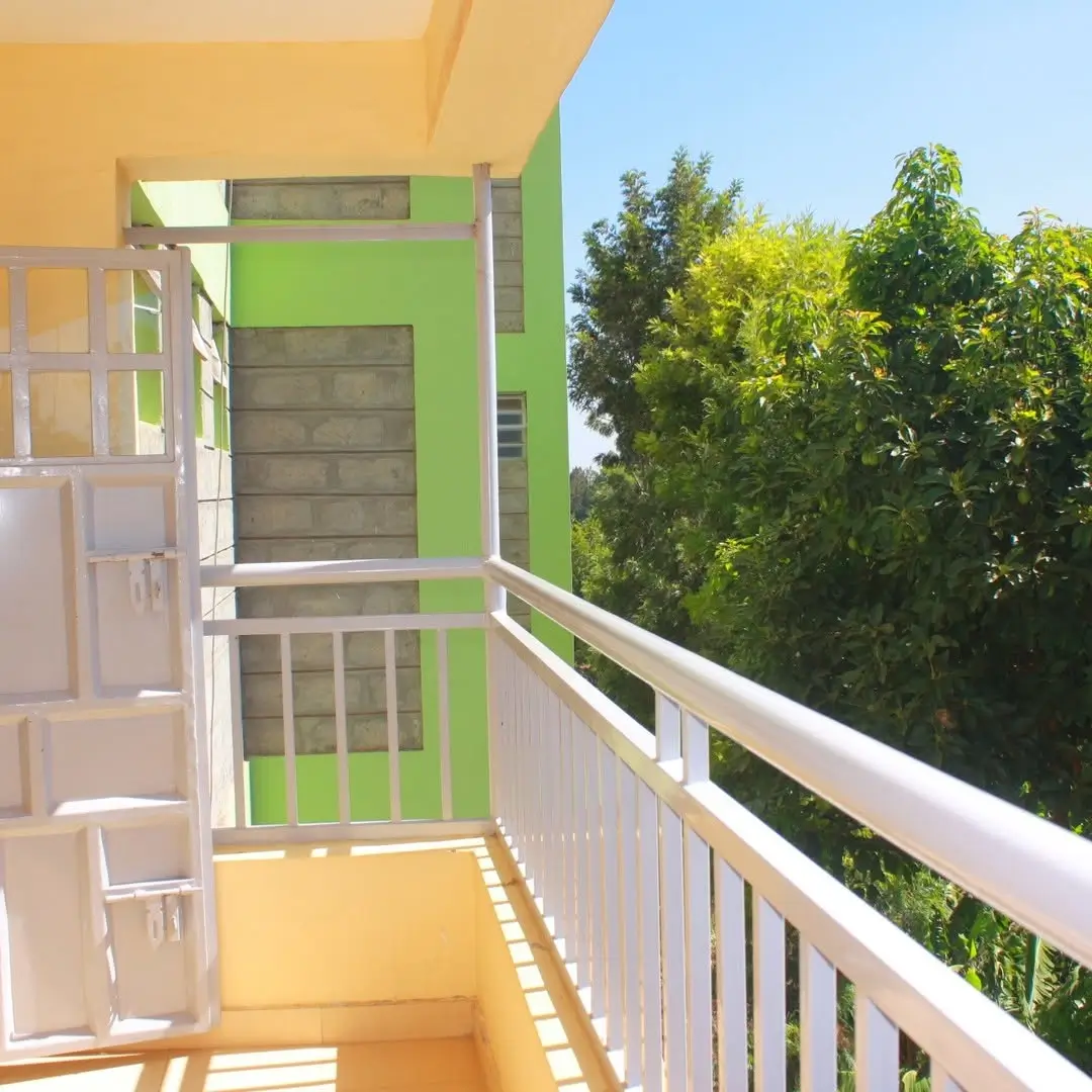 Bright balcony with white railing overlooking lush green trees