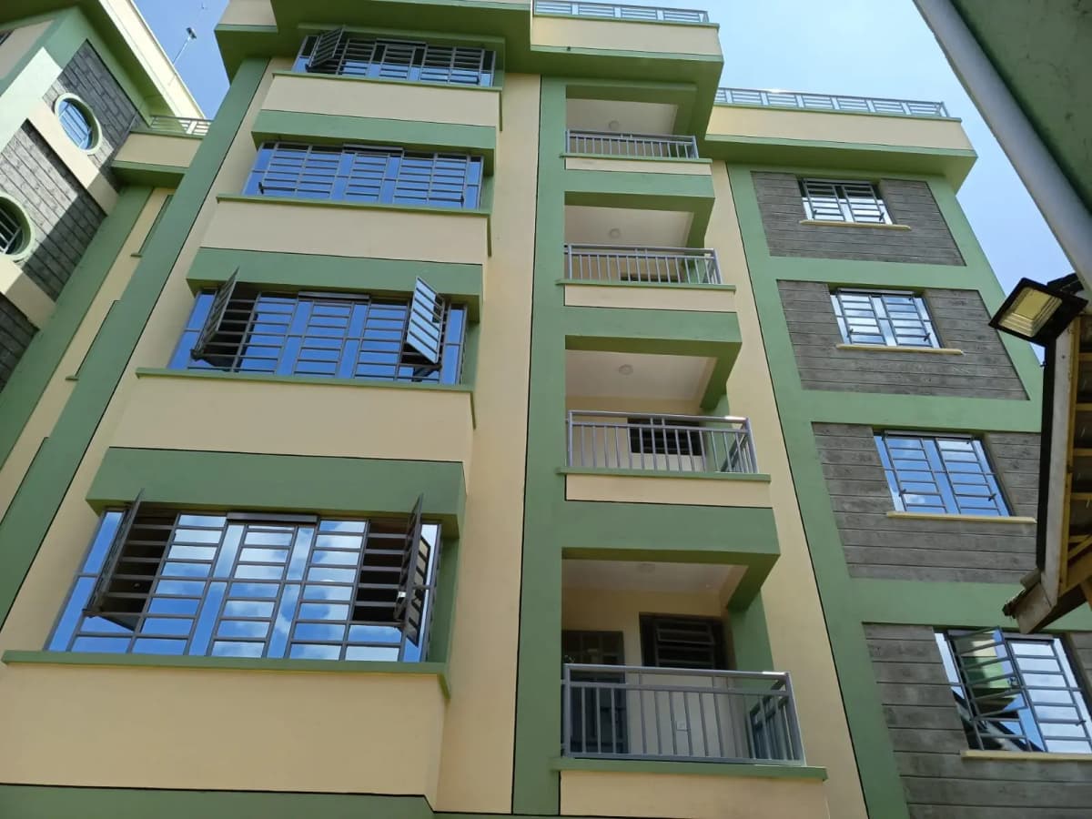 Multi-story residential building facade with green and cream exterior
