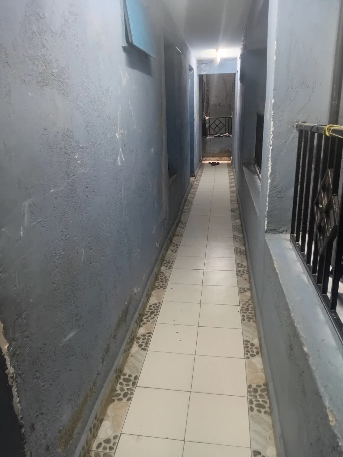 Narrow interior hallway with tile flooring and plain walls