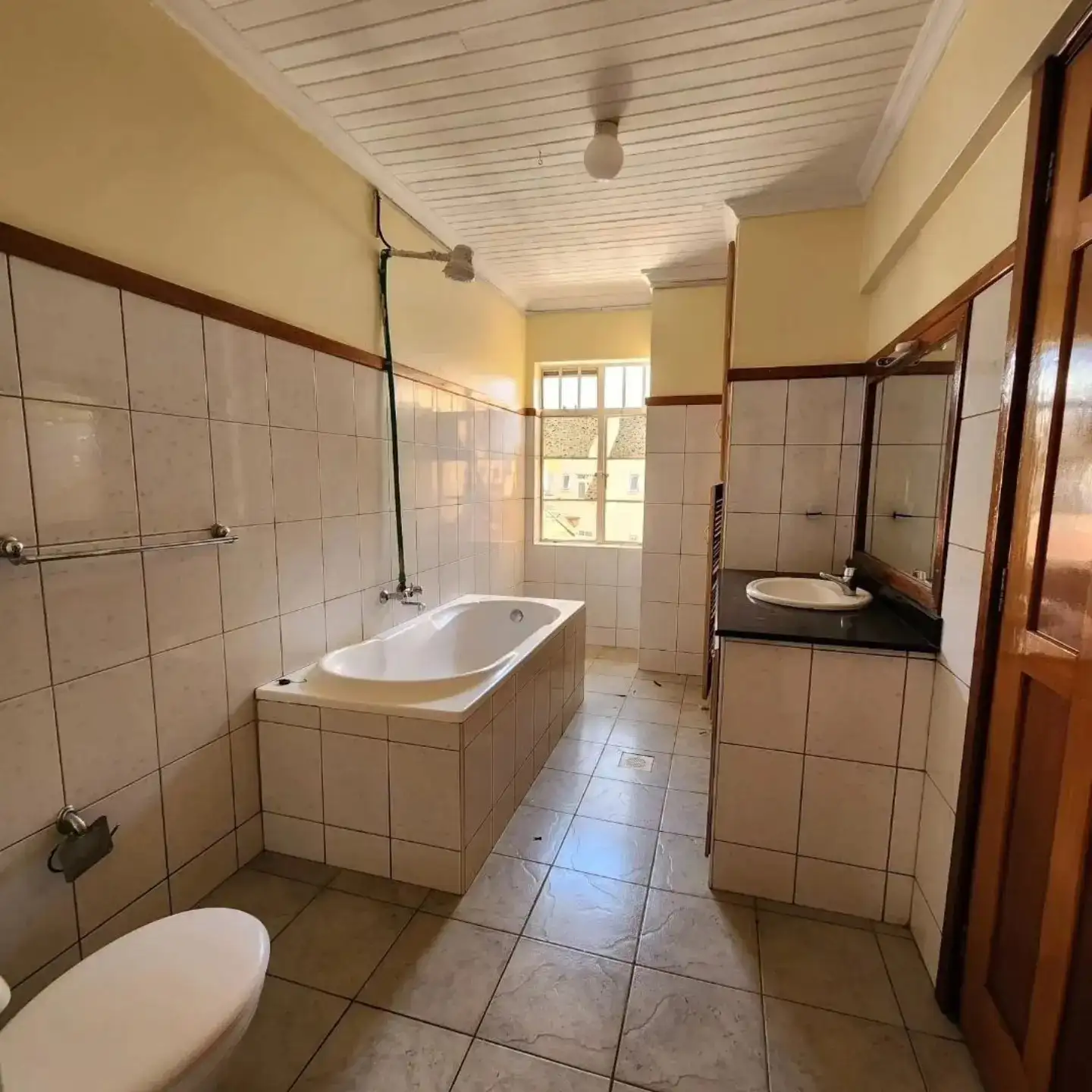 Spacious bathroom with bathtub, toilet, and sink vanity