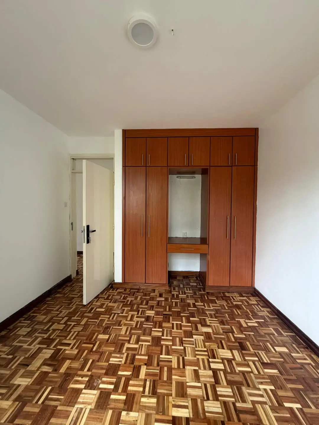 Spacious bedroom with wooden wardrobe and parquet flooring