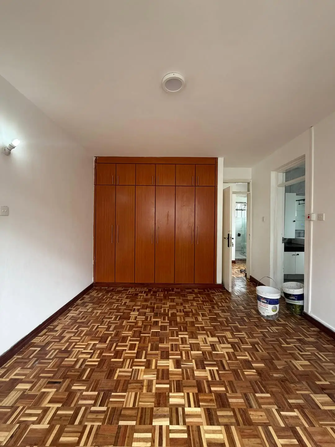 Empty bedroom with wooden wardrobe and parquet flooring