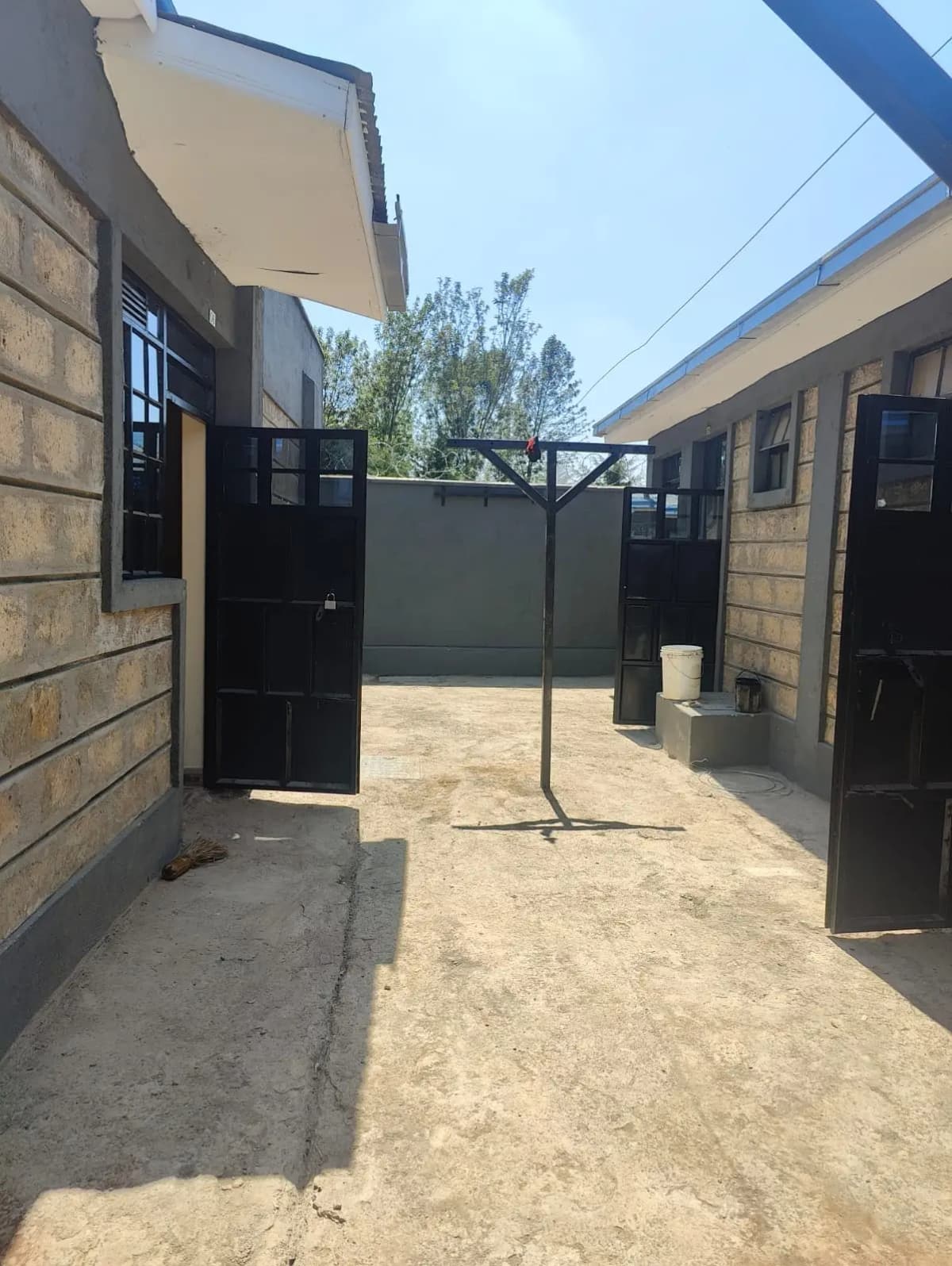 Compound courtyard with black metal gate and stone walls
