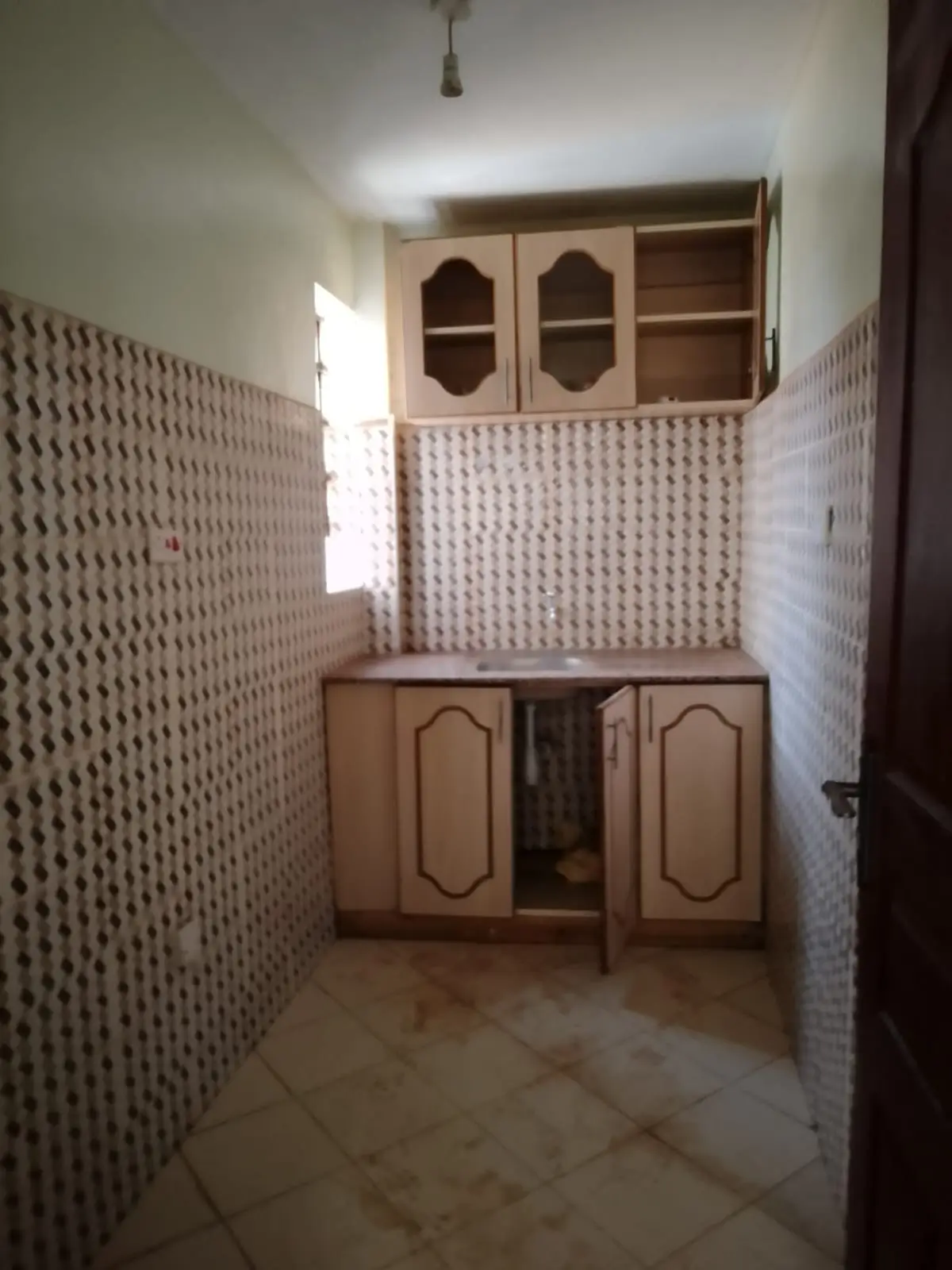 Compact kitchen with patterned tile walls and wooden cabinetry