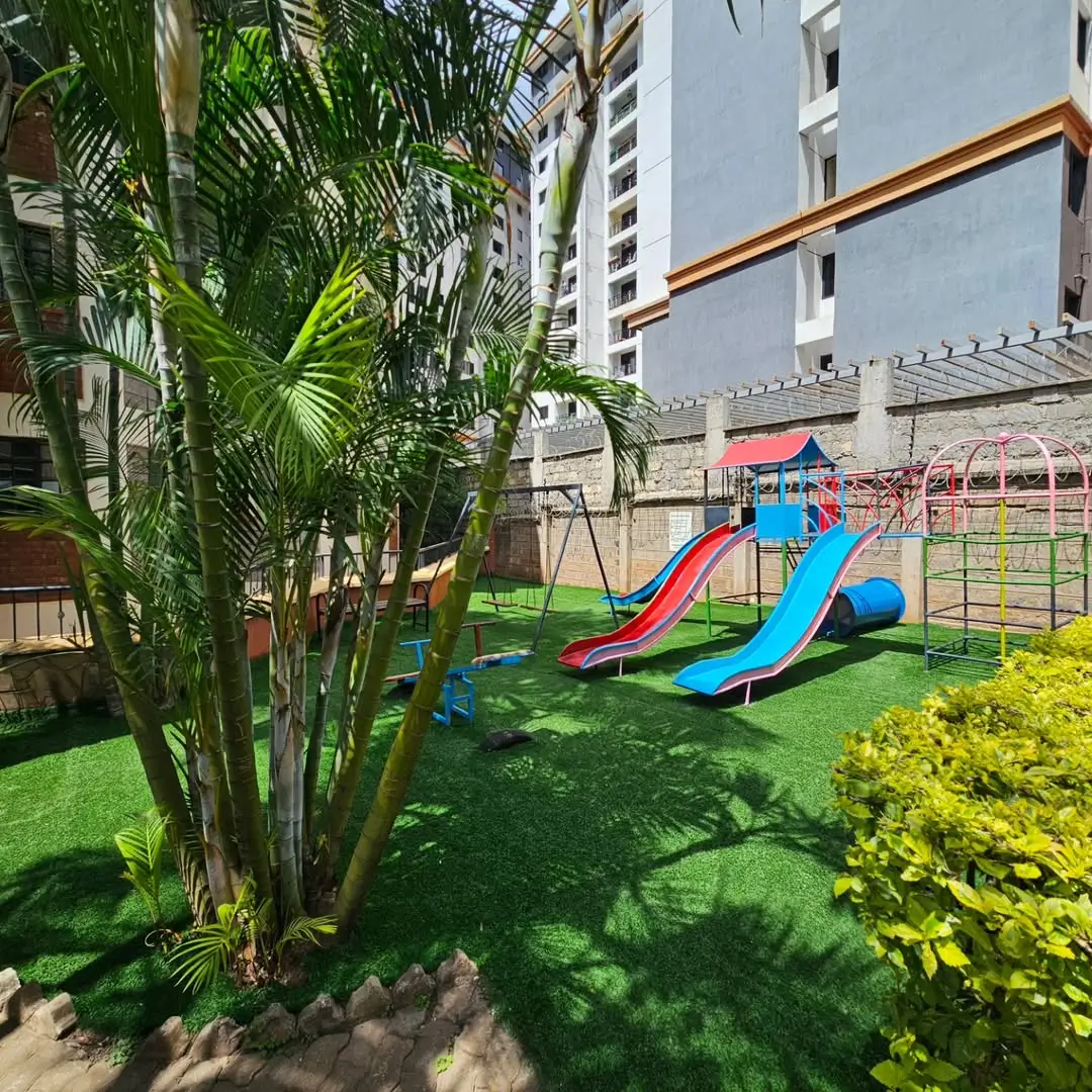 Landscaped compound with playground, palms, and manicured lawn