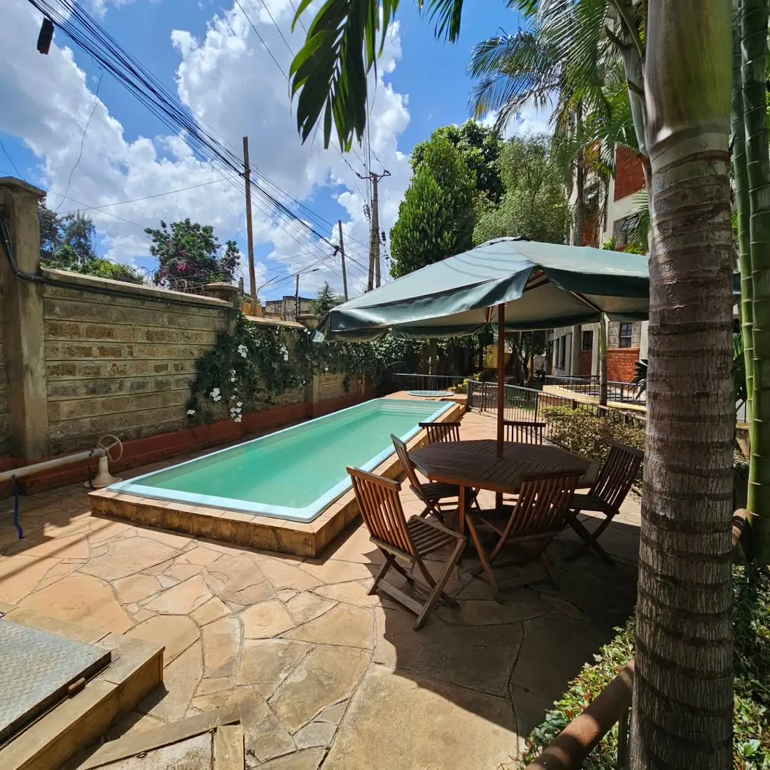 Rectangular swimming pool with shaded seating area and palm trees