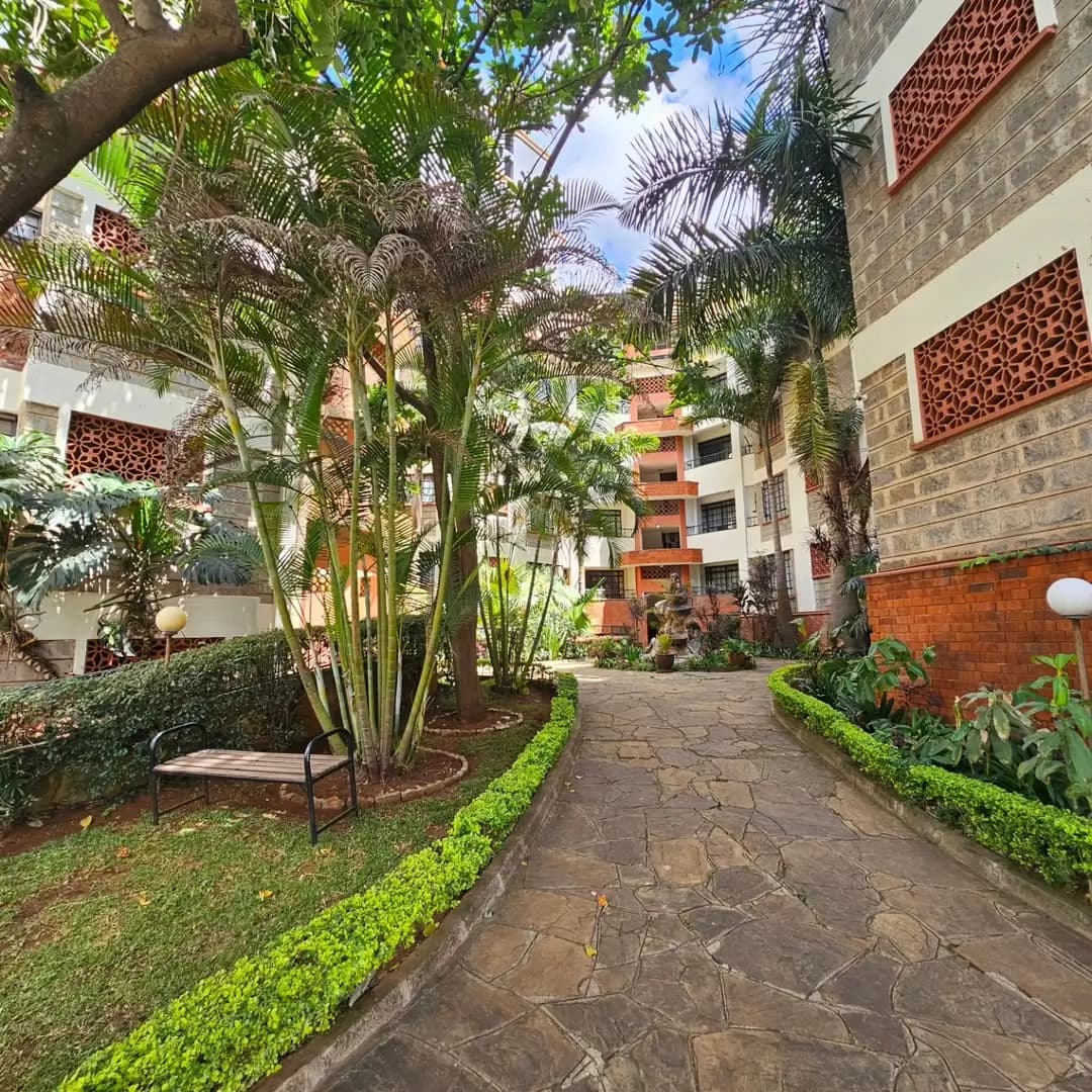 Lush compound courtyard with mature trees and manicured hedges