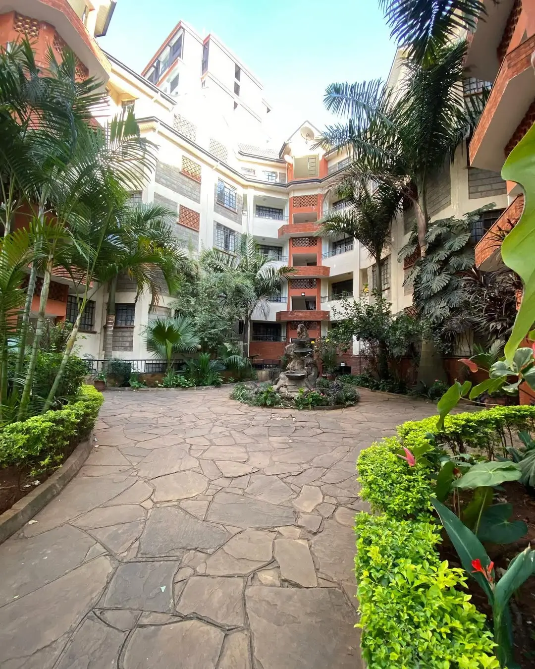 Lush compound courtyard with tropical plants and paved walkway