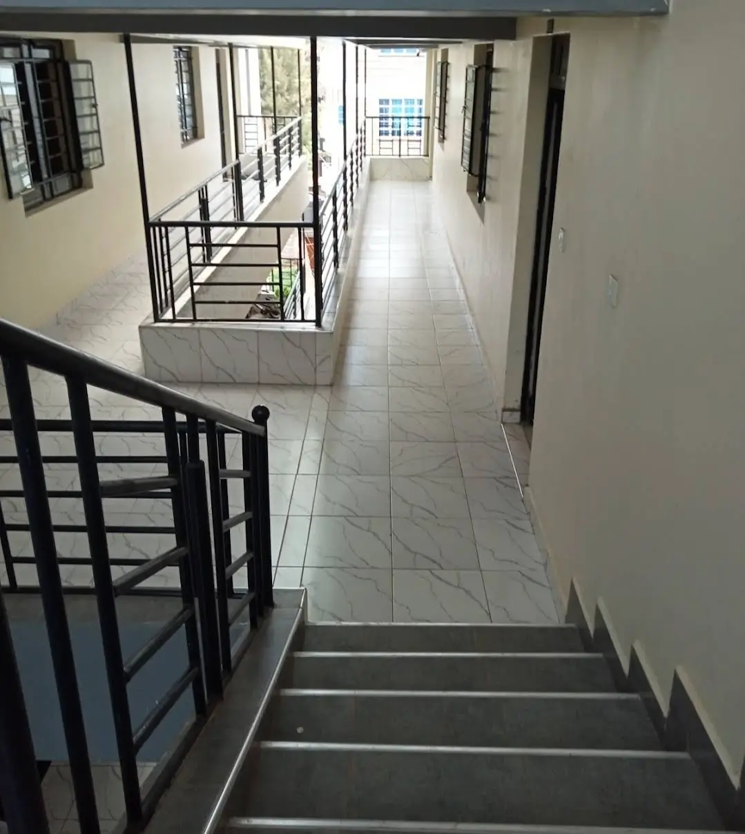 Clean hallway with stairs and black metal railings
