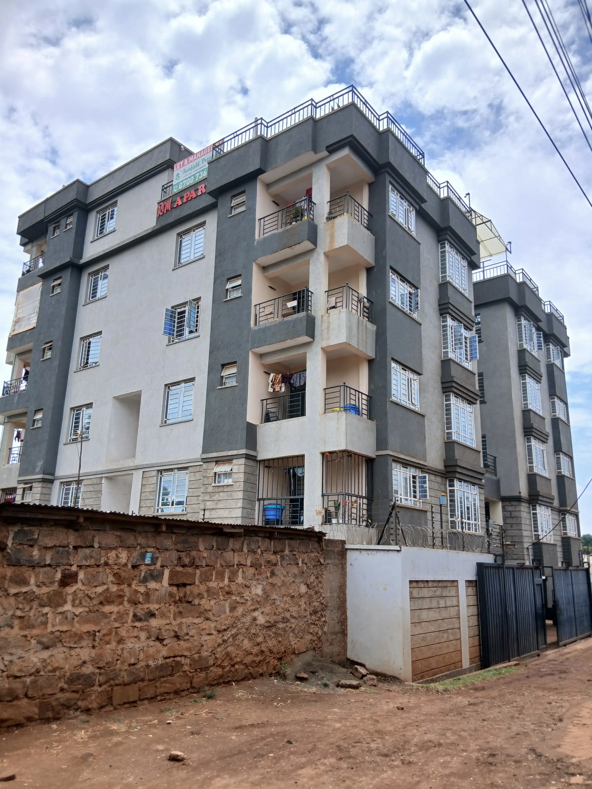 Multi-story residential building with balconies and compound wall