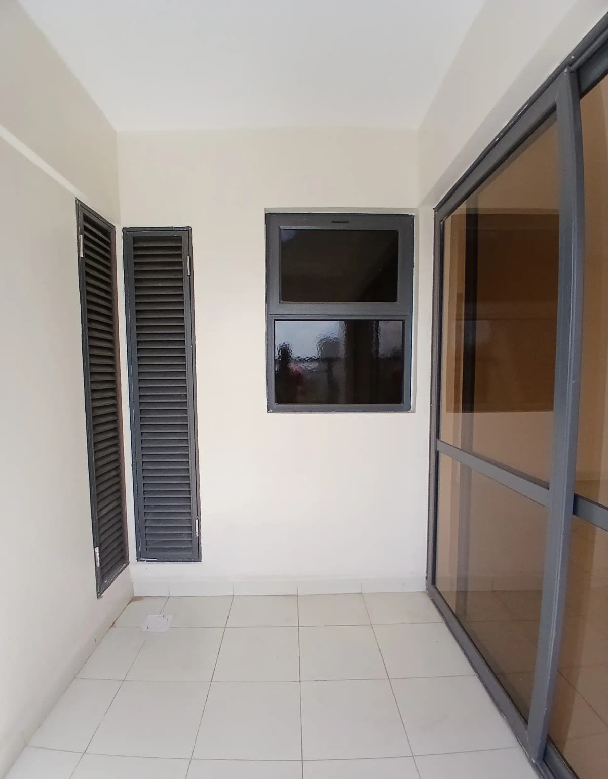 Narrow balcony with sliding glass doors and louvered vents